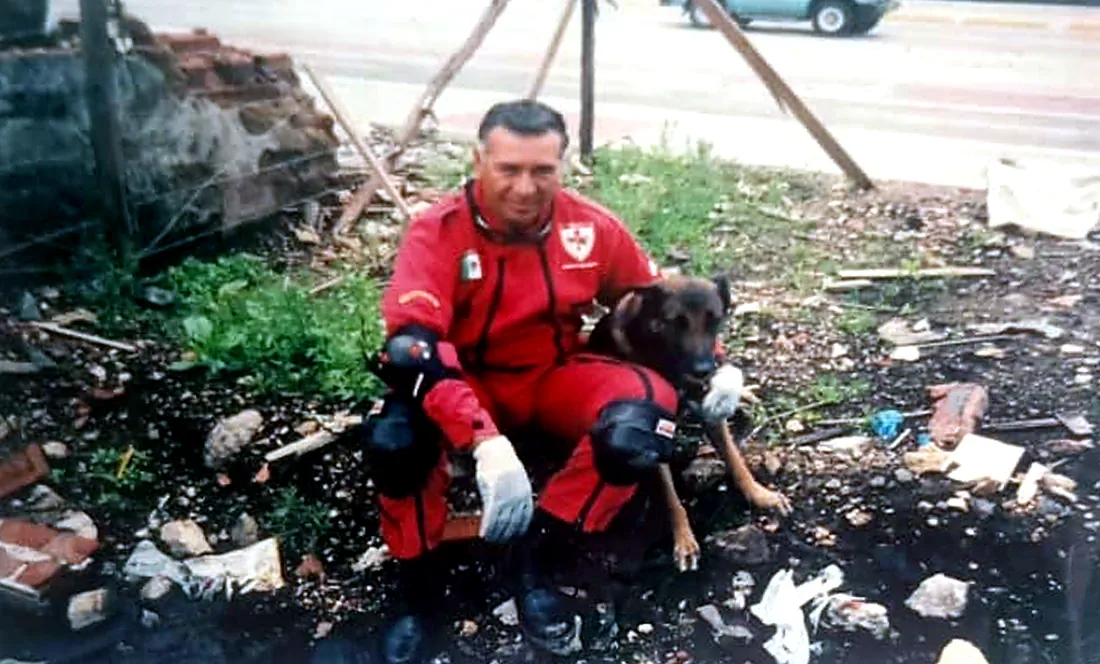 Rodolfo Núñez con uniforme rojo de rescate y su perra Oma sobre escombros en Bogotá, 2006