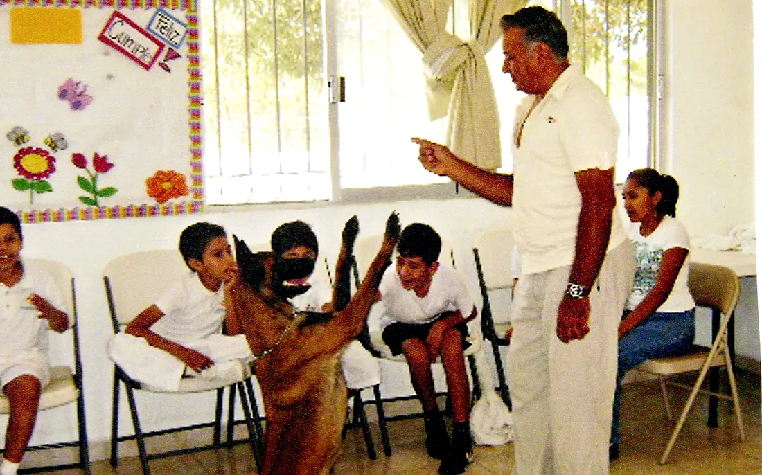 Rodolfo Núñez guía a un pastor belga malinois durante una sesión de terapia con niños en un aula